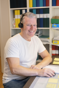 glad man med headset i kontorsmiljö tar emot samtal om VVS-jour i Vega