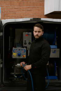 Spolmontör i arbetskläder står framför ett spolaggregat monterat i en öppen Renault Trafic, redo för stamspolning.